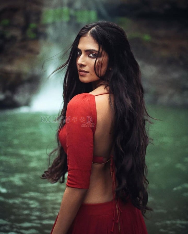 Sensuous Malavika Mohanan in a Bold Red Blouse with Matching Red Skirt Standing in Front of a Waterfall Photoshoot Pictures 01