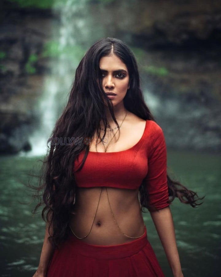 Sensuous Malavika Mohanan in a Bold Red Blouse with Matching Red Skirt Standing in Front of a Waterfall Photoshoot Pictures 02
